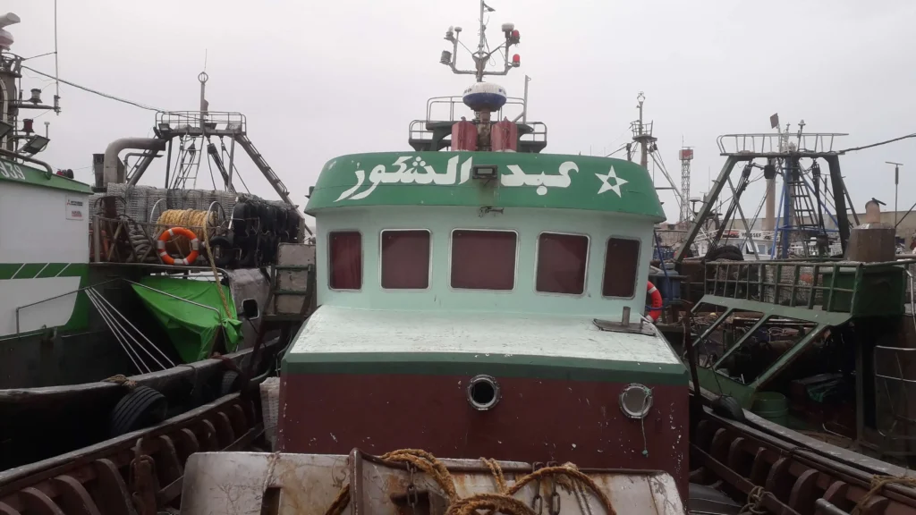 Photo du bateau de pêche traditionnel Abd Achchakour en mer à Essaouira, capturant des poissons frais pour le Restaurant Café El Azzam.
