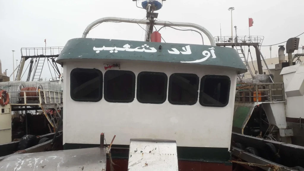 Photo du bateau de pêche traditionnel Ouled Cheib en mer à Essaouira, capturant des poissons frais pour le Restaurant Café El Azzam.